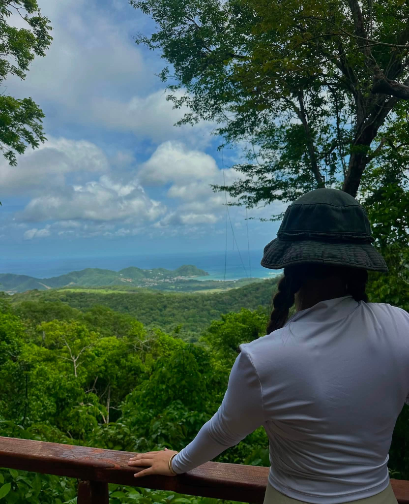 1. Guest looking across tropical forest and distant hills from a scenic overlook at Cala Azul
