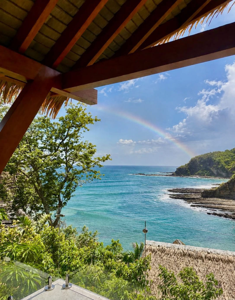 Pacific coastline and tropical vegetation viewed from Cala Azul beneath a rainbow